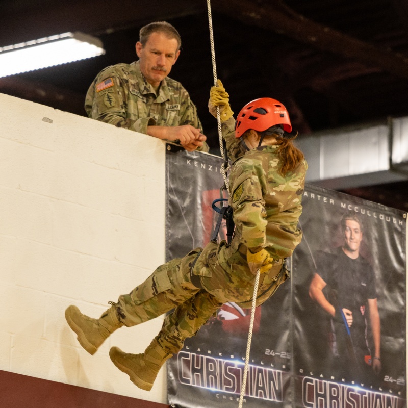 student rappelling in gym