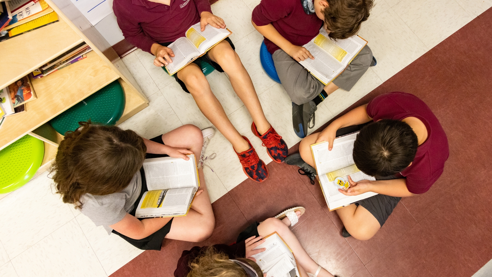 5 children reading bibles on the floor of a classroom