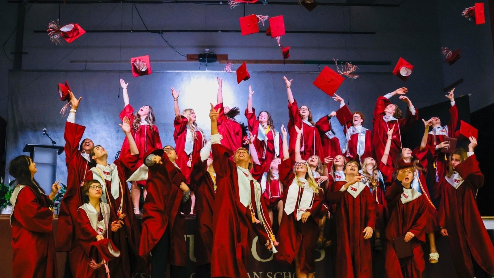 Graduates in maroon gowns throwing their caps into the air