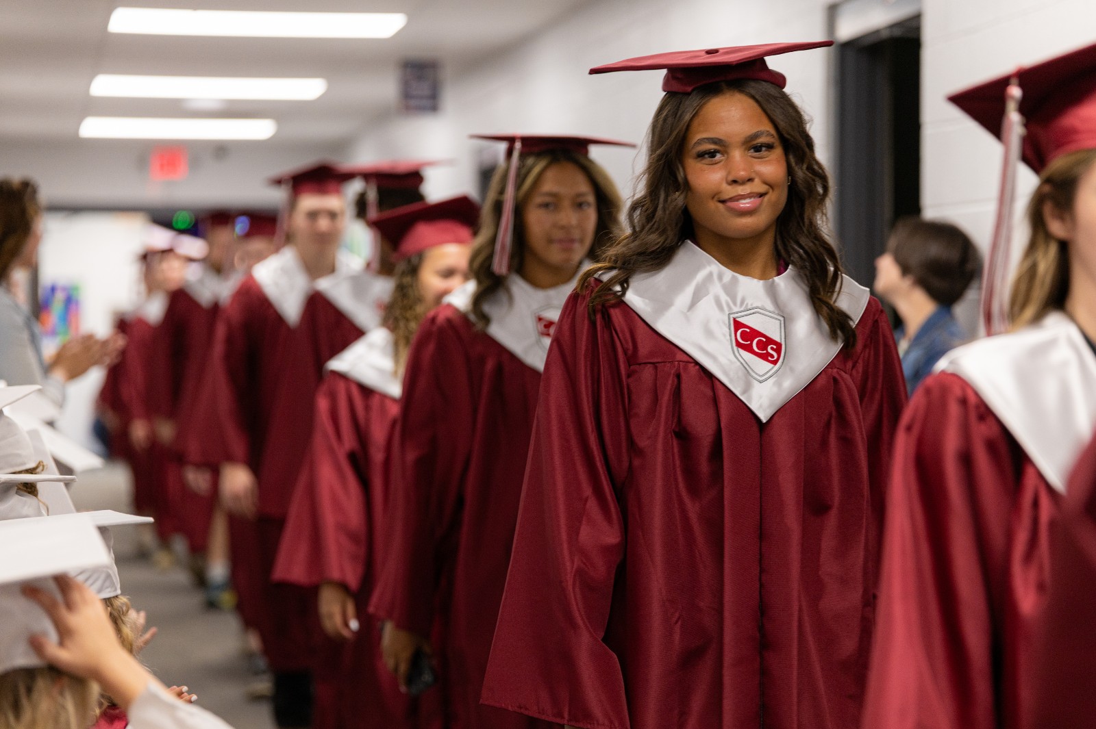 graduate in maroon walking down a pre-k hallway
