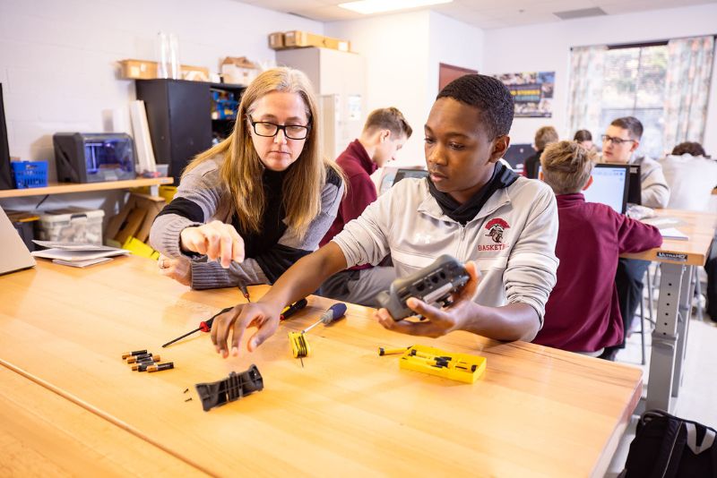 female teacher and male student sitting at desk assembling controller